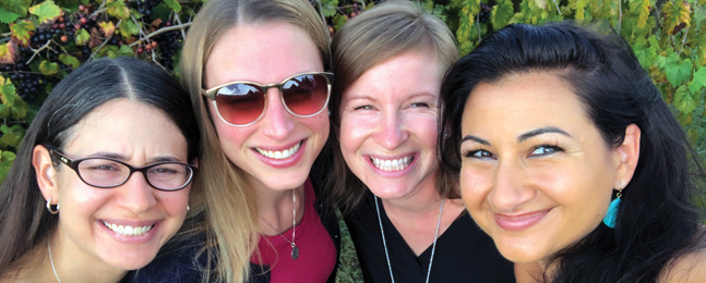 Close-up of the faces of four smiling women.